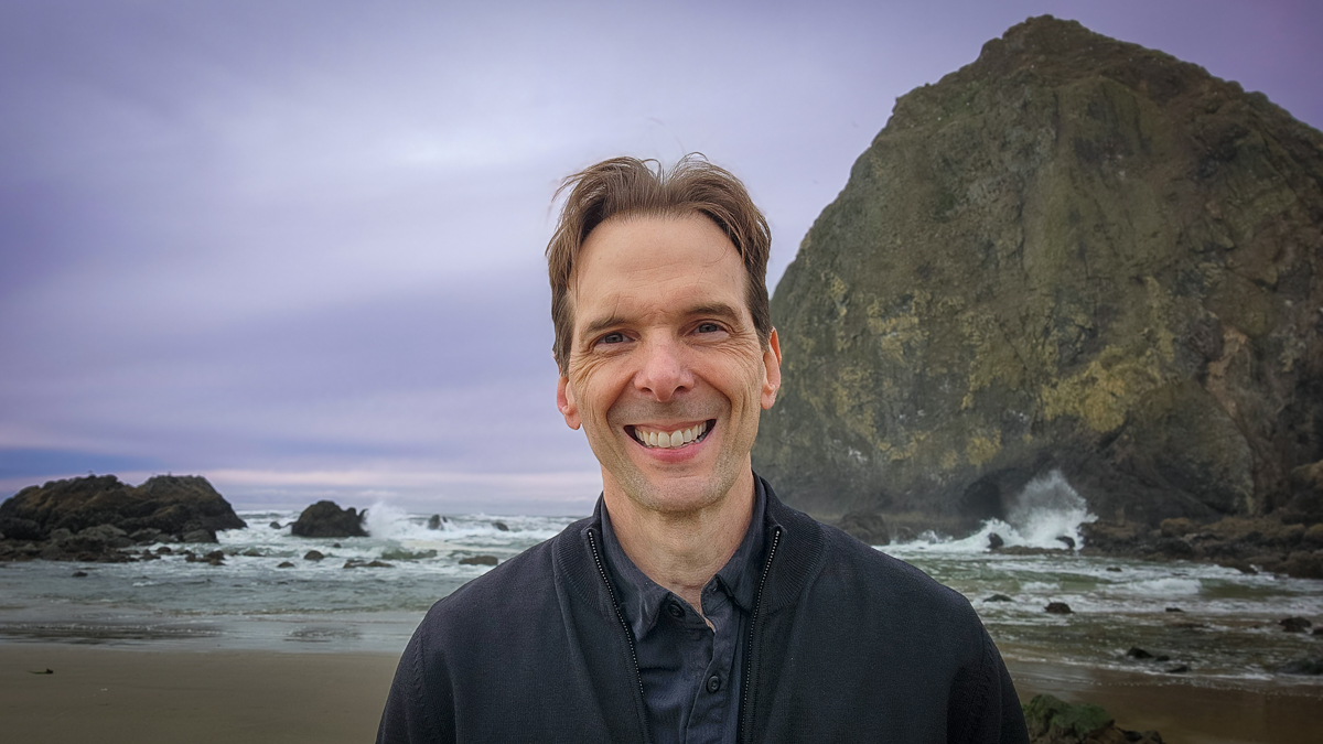 Motivational speaker Larry Weaver smiling near Haystack Rock in Cannon Beach, Oregon