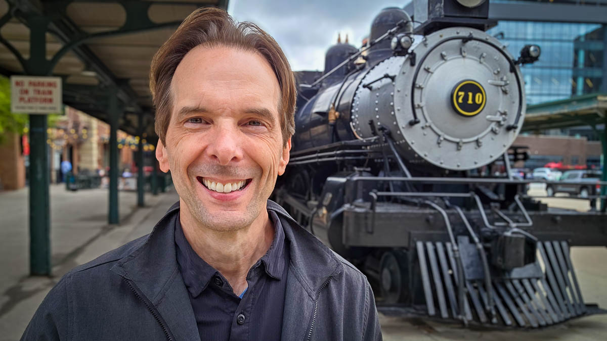 Larry Weaver standing near a locomotive at Iron Horse Park in Lincoln, Nebraska.