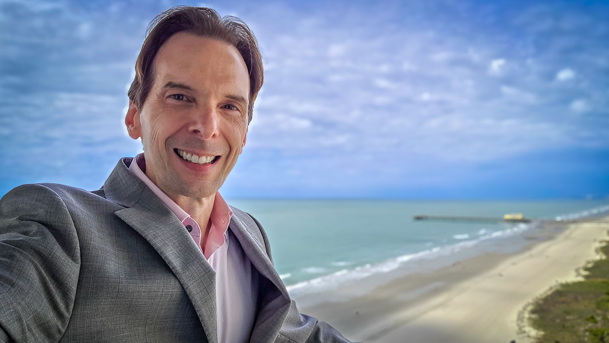 Motivational speaker Larry Weaver posing with the beach and Atlantic Ocean along the Grand Strand in the background