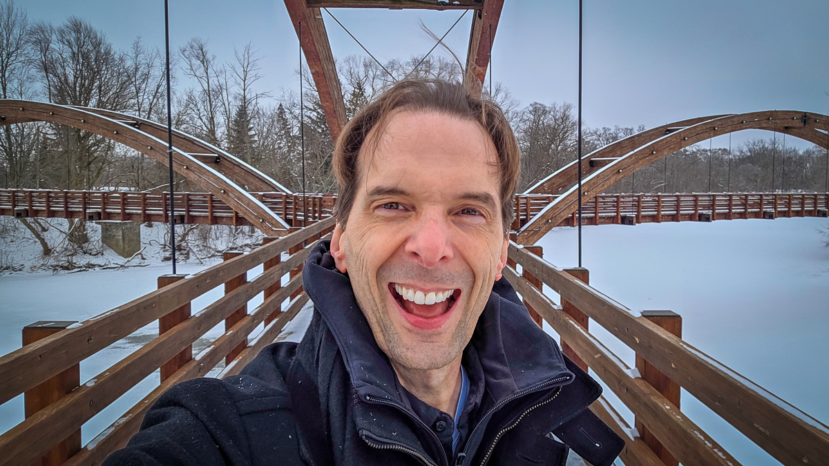 Motivational speaker Larry Weaver smiling in the snow at The Tridge in Midland, Michigan