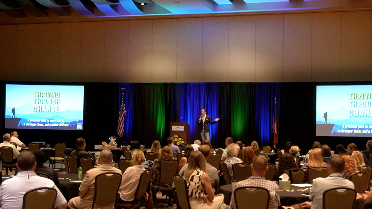 Larry Weaver speaking onstage for electric cooperative marketing, member services, and communications professionals during a conference at The Island Convention Center in Jekyll Island, Georgia.
