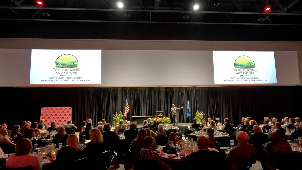 Larry Weaver speaking onstage for agricultural leaders during an annual convention at The Box Elder Events Center near Rapid City, South Dakota.