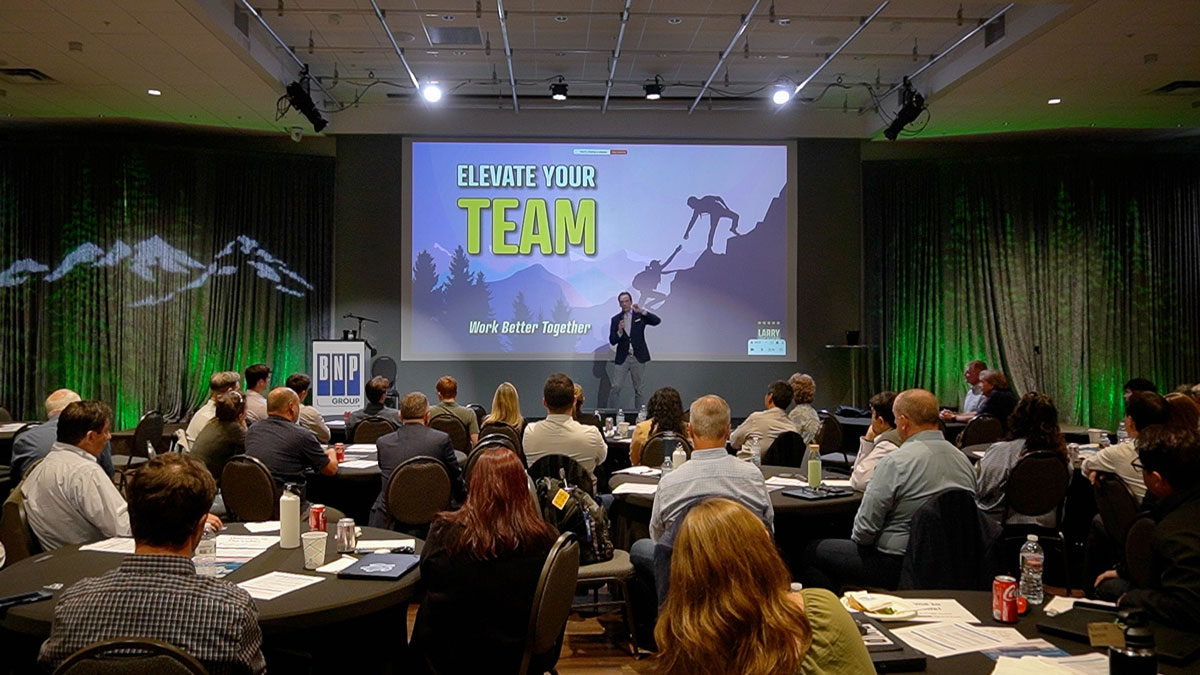 Larry Weaver speaking onstage for a global group of aviation engineering professionals during a company educational event at MCA - The Cube in Denver, Colorado.