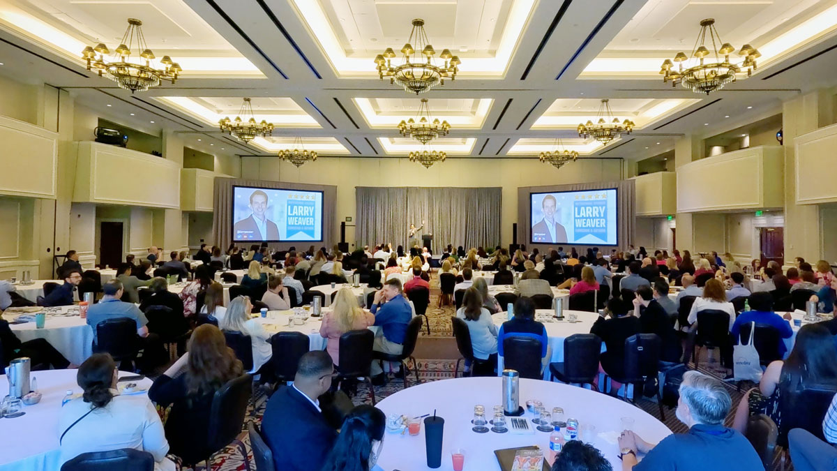 Larry Weaver speaking onstage for government finance professionals during a spring conference at Williamsburg Lodge in Williamsburg, Virginia.