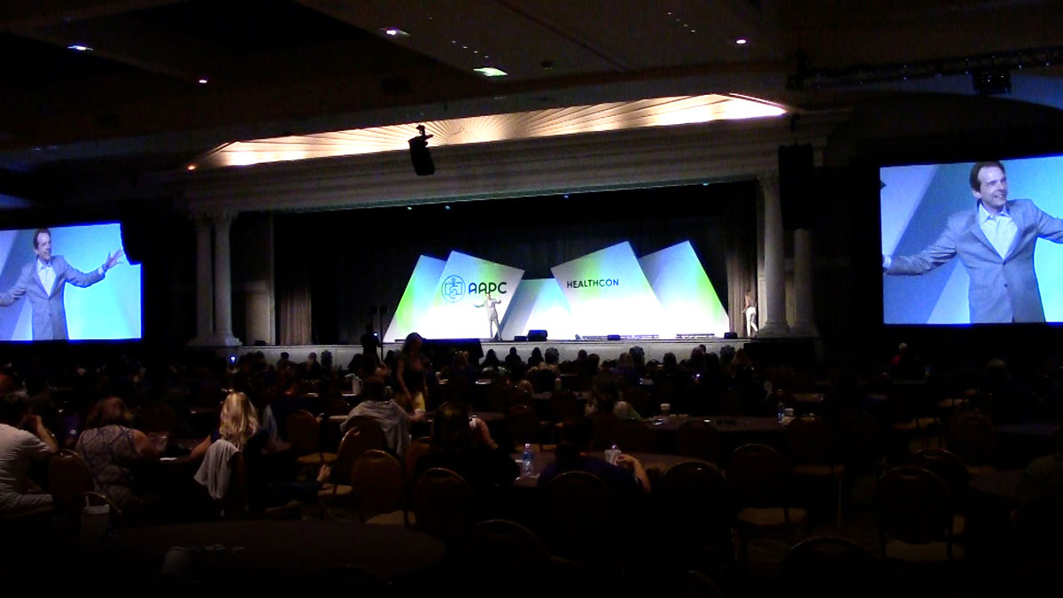 Larry Weaver speaking onstage for a crowd of 1,500 medical coding professionals during HEALTHCON at Gaylord Opryland Resort & Convention Center in Nashville, Tennessee.