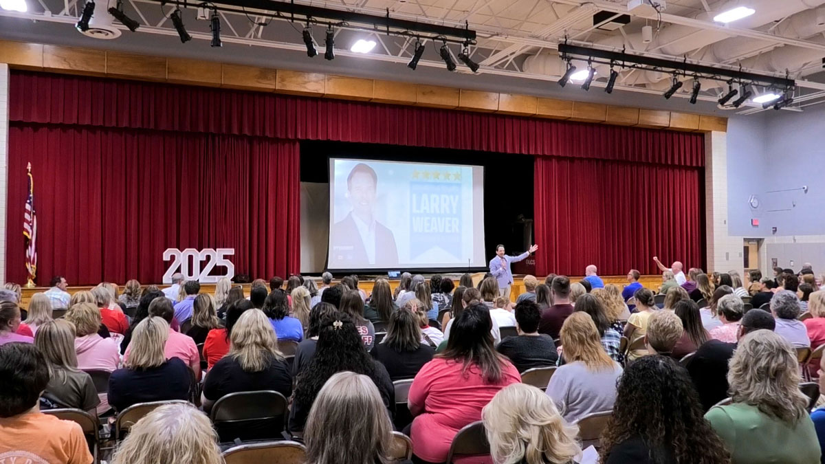 Larry Weaver speaking onstage for public school educators during a teacher in-service at River High School in Hannibal, Ohio.