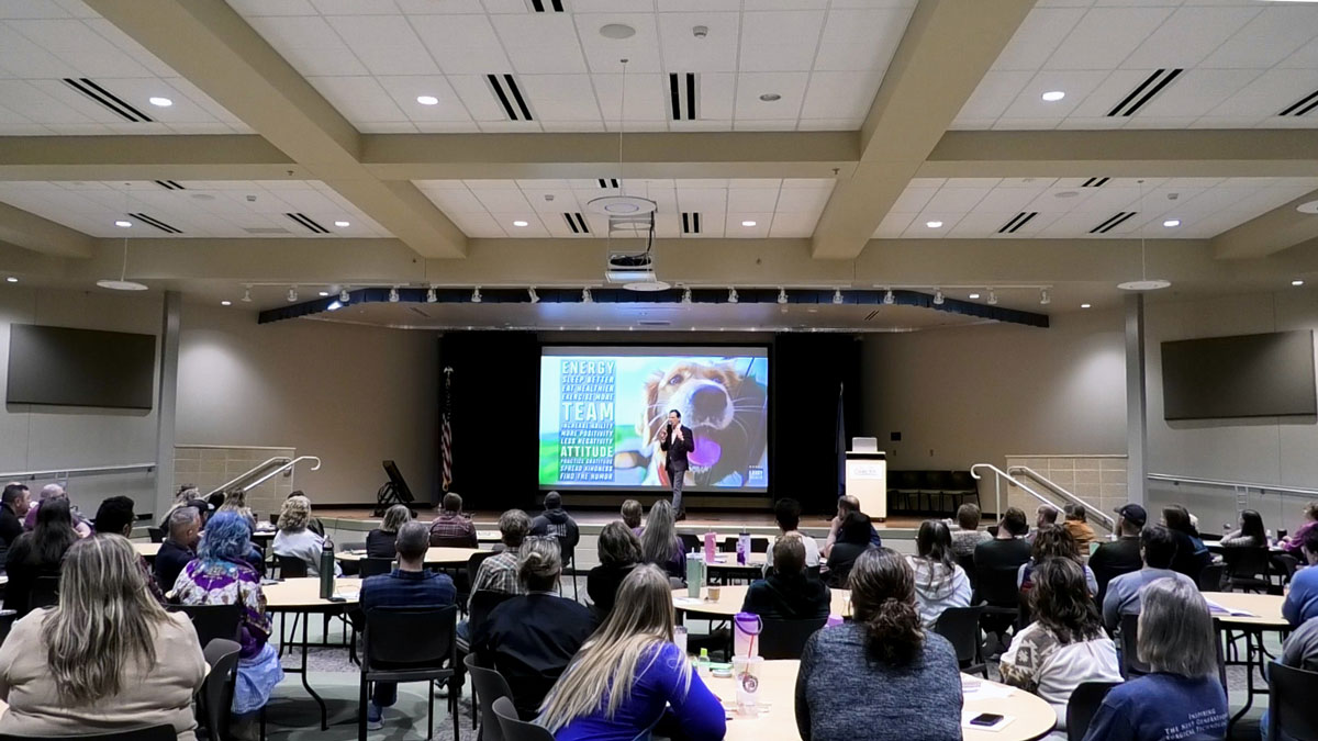 Larry Weaver speaking onstage for technical college faculty and staff during an in-service event in Rapid City, South Dakota.